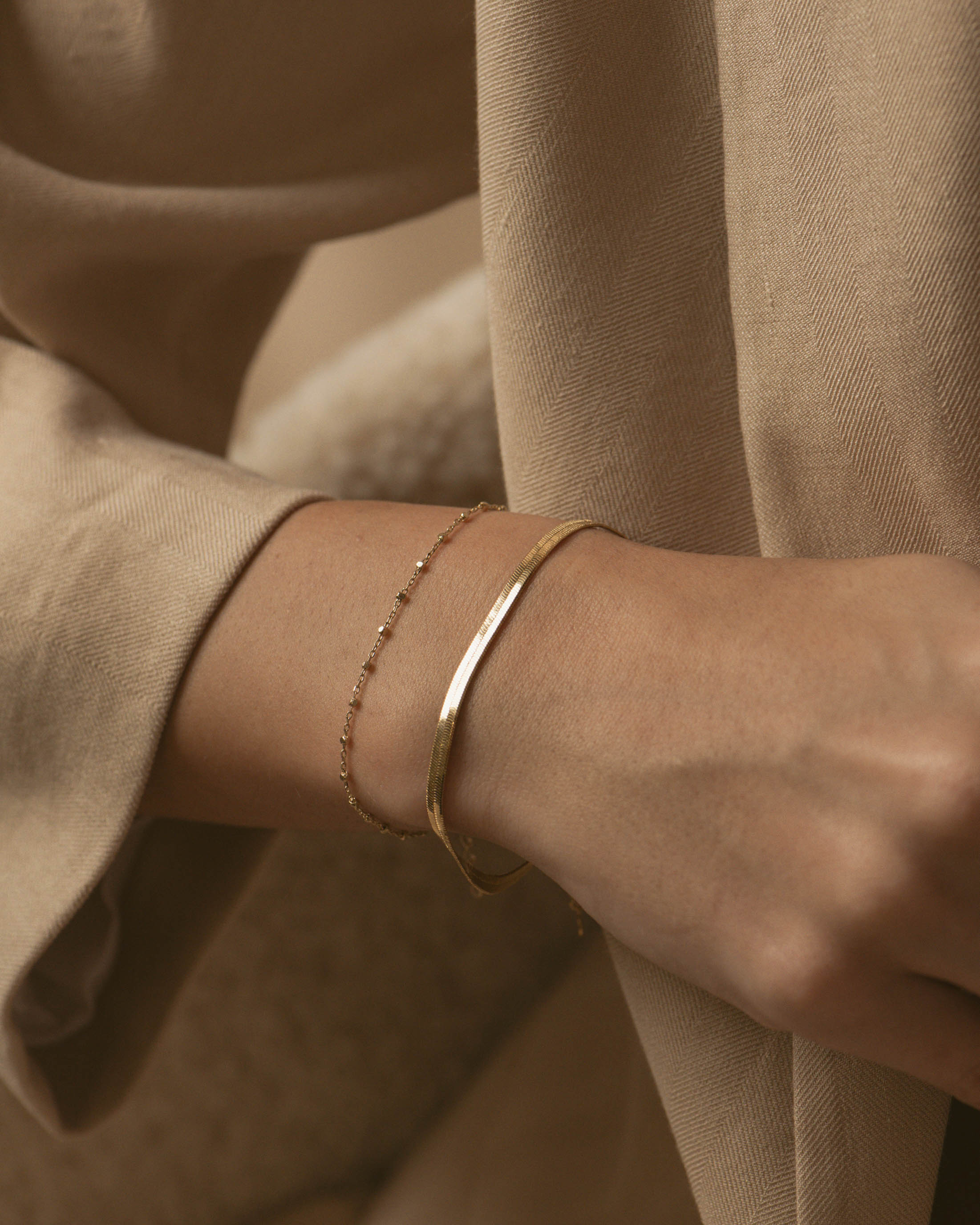 Association de bracelets en plaqué or 18 carats, composée d'un bracelet en chaîne plate, et d'un bracelet en chaîne fine avec des petites mailles carrées, fabriqués en France.
