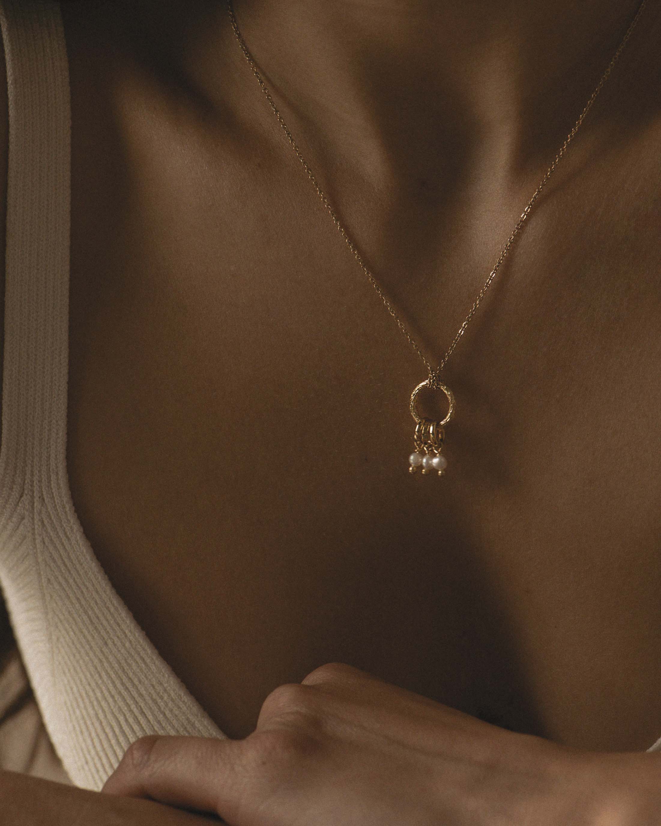 Collier composé d'un pendentif en anneau rayé avec trois anneaux pendants et trois perles de culture rondes en plaqué or 3 microns fabriqué en France. 