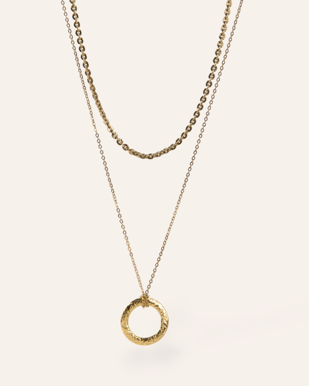 Composition de deux colliers, avec un collier en maille soleil, et un collier en chaîne forçat avec un pendentif en anneau plat texturé au motif de style vintage en plaqué or 18 carats.