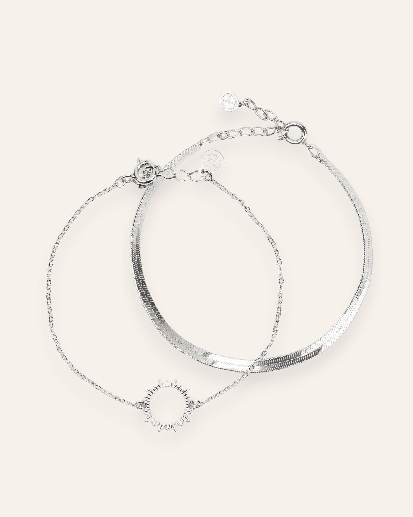 Composition de deux bracelets, avec un bracelet en chaîne plate en argent 100% recyclé, et un bracelet en chaîne fine habillée d'un soleil ajouré en argent massif 925.
