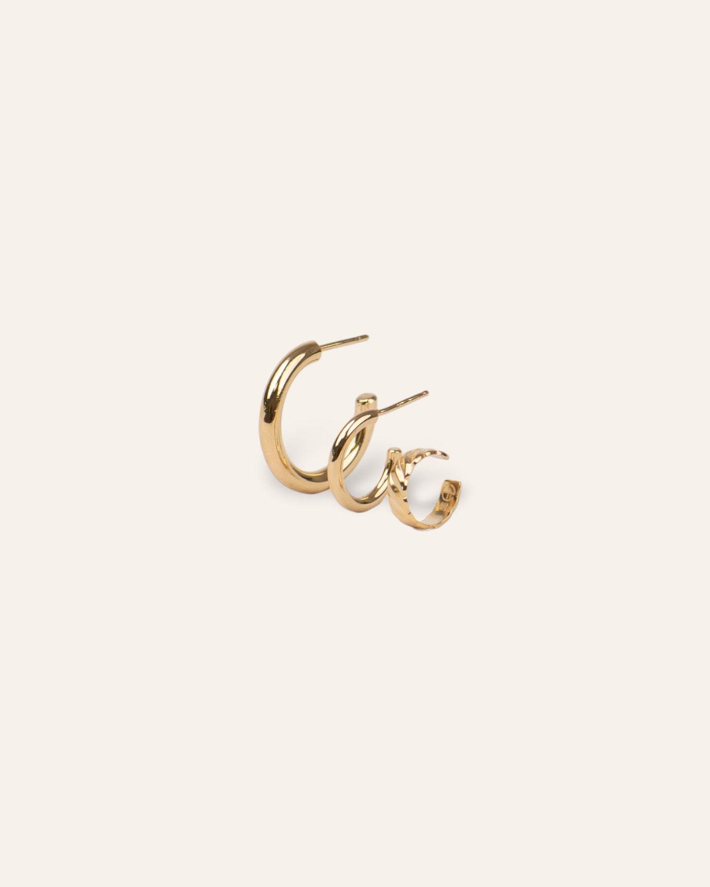Composition de trois boucles d'oreilles, avec une petite créole en anneau lisse, une mini créole en anneau lisse, et un earcuff au motif wavy en plaqué or 18 carats made in France.
