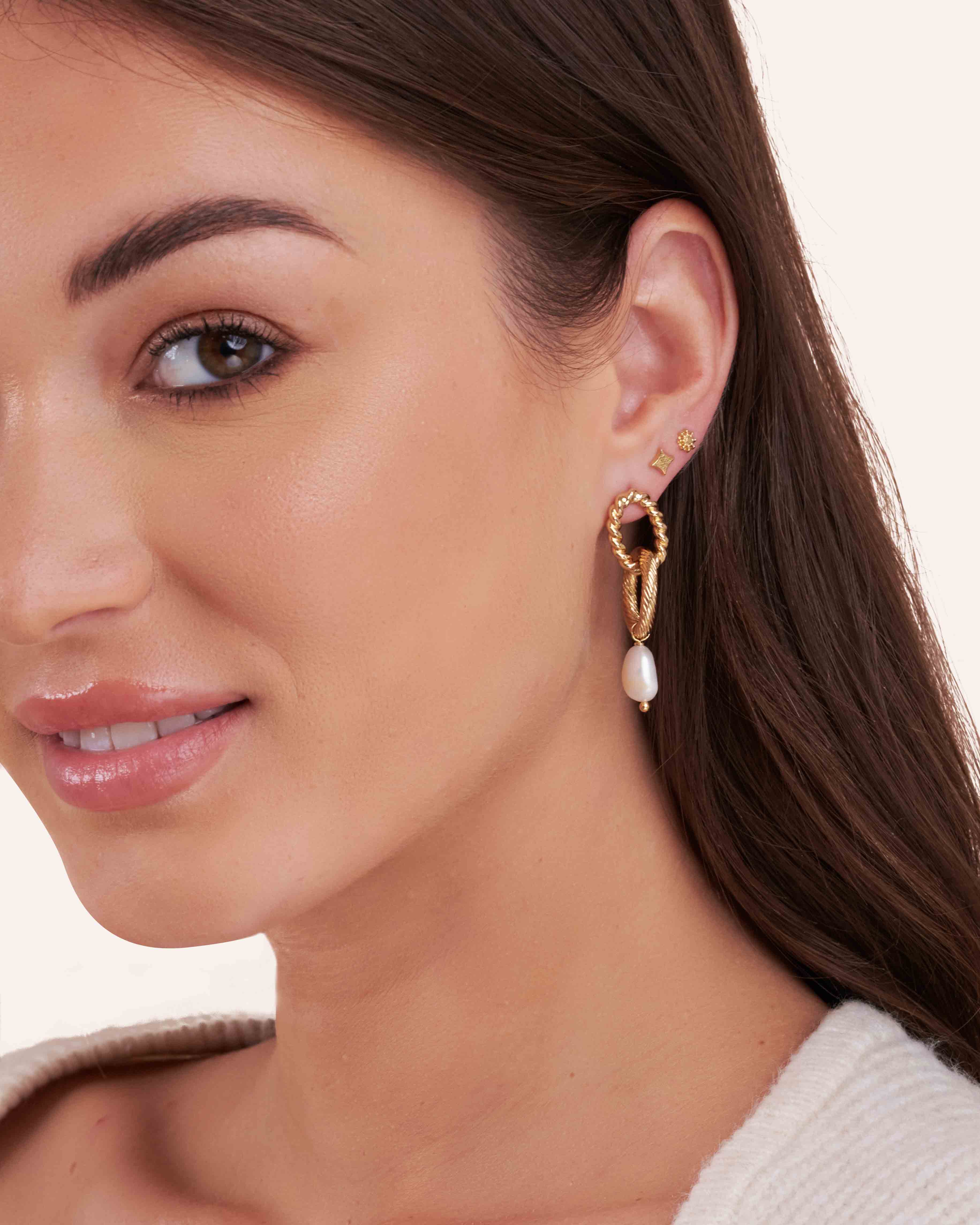 Association de trois boucles d'oreilles composée d'une boucle pendante composée de deux anneaux torsadé et strié et d'une perle de culture de forme ovale, d'une petite boucle puce en forme de losange, et d'une petite boucle puce en forme d'étoile made in France.