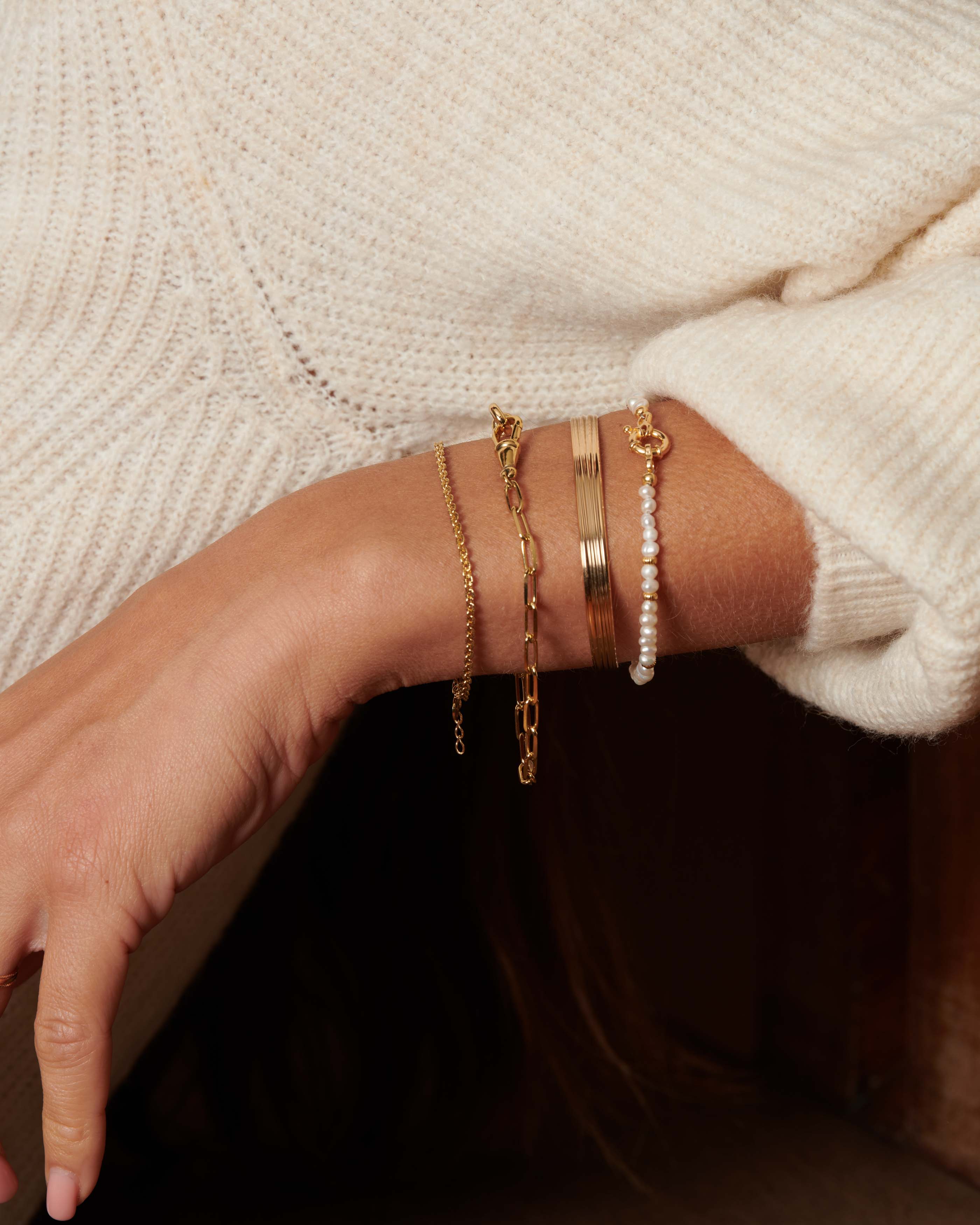 Set of ethical bracelets, 3-micron gold-plated, Made in France: a fine sun-link bracelet, a chain with wide rectangular links, a wide striped bangle, and a fine cultured-pearl bracelet with small gold-tone beads.
