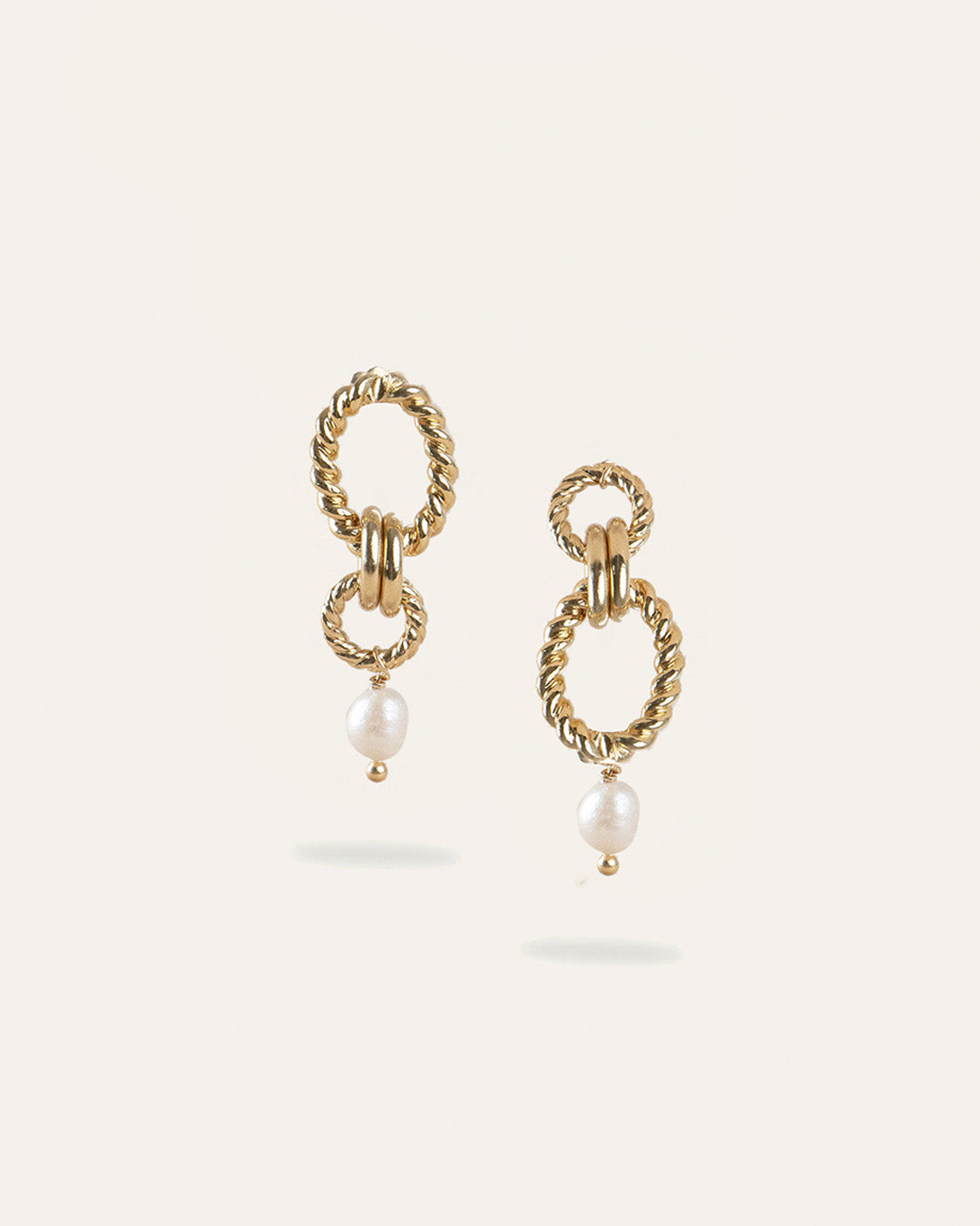 Boucles d'oreilles en plaqué or 3 microns composées de deux anneaux torsadés et de deux anneaux lisses de différentes tailles avec une perle de culture pendante fabriquées en France.