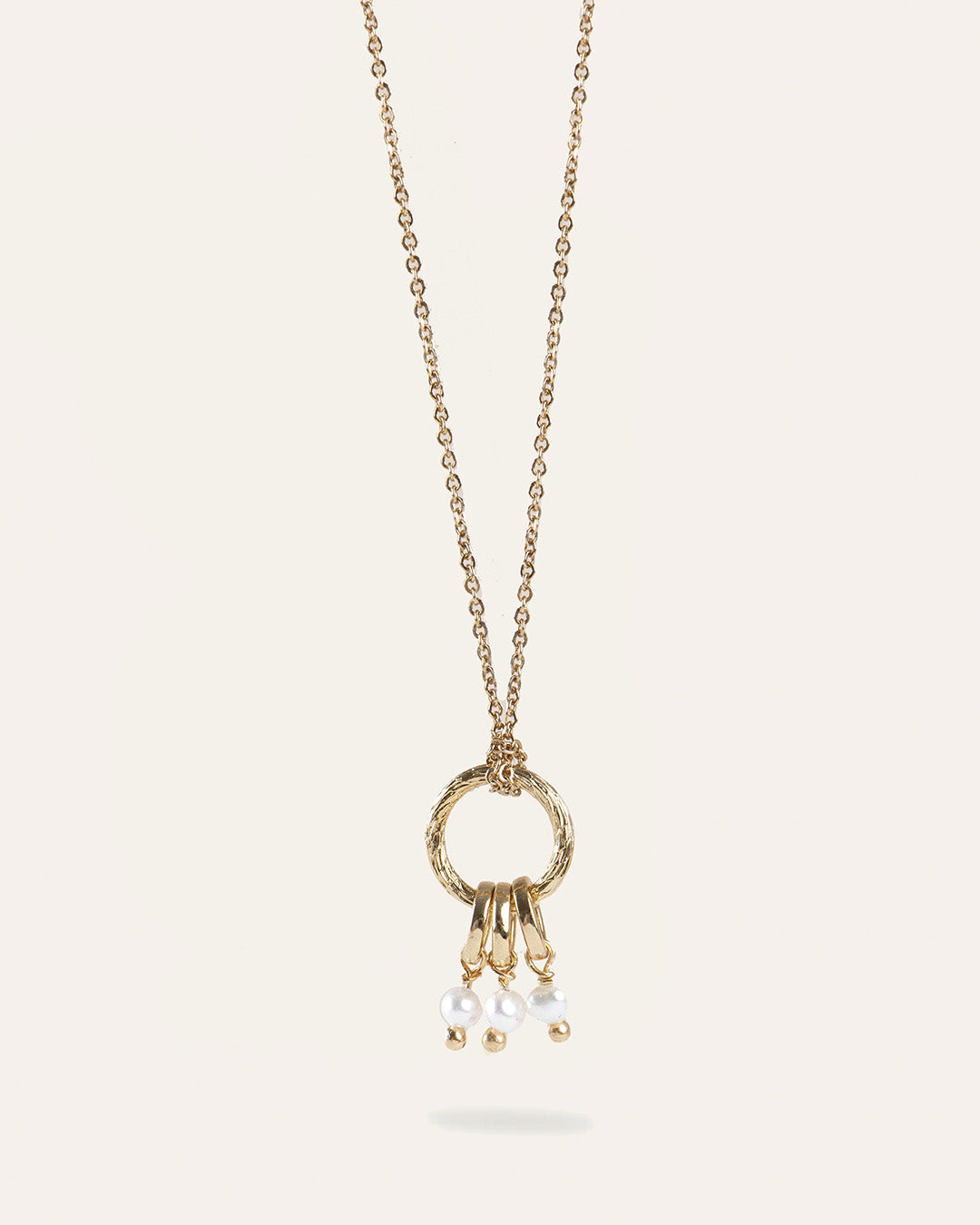 Collier en chaîne forçat avec un pendentif en anneau rayé, et trois anneaux pendants avec trois petites perles de culture made in France.