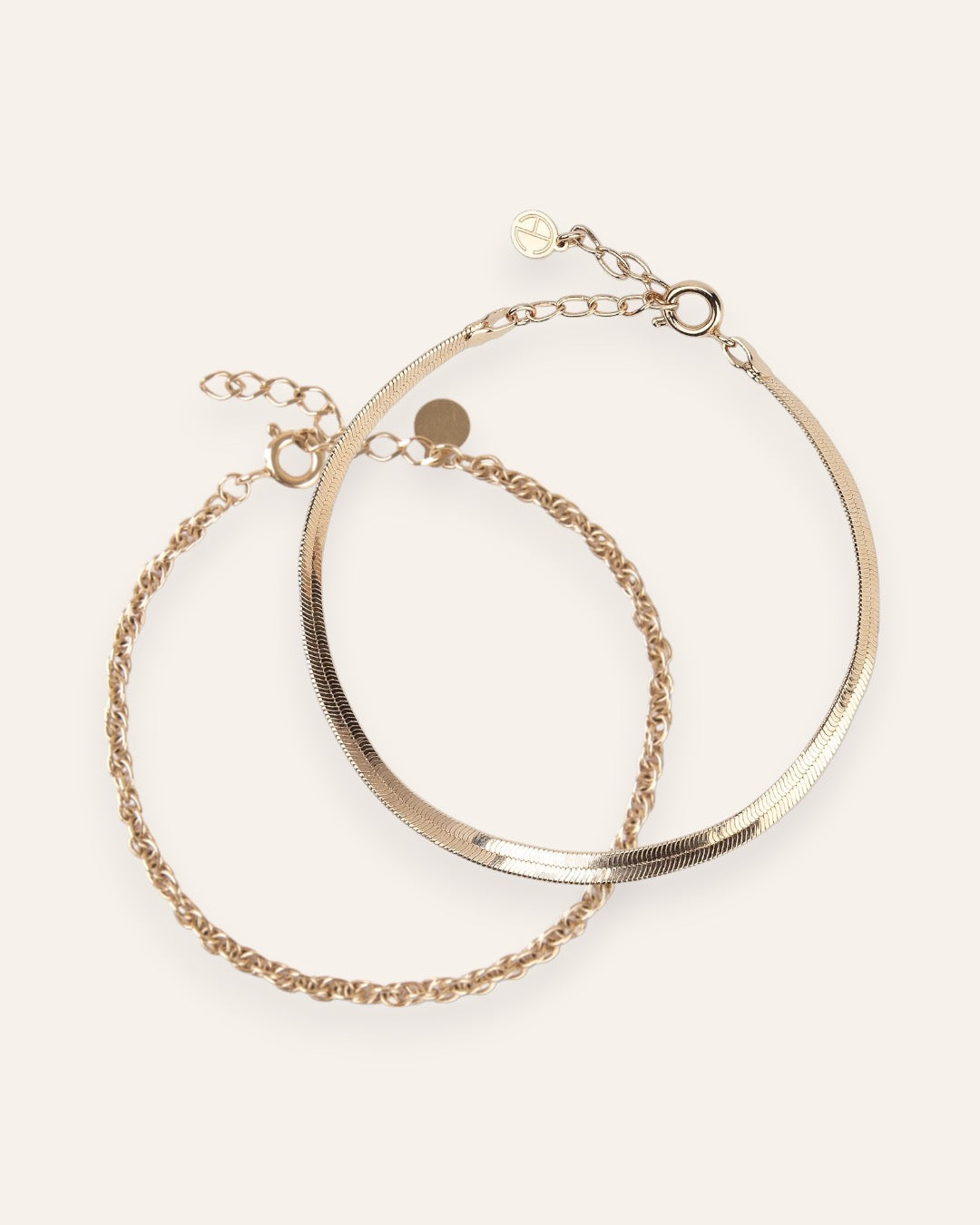 Composition de deux bracelets, avec un bracelet en chaîne plate et un bracelet en chaîne torsadée en plaqué or 18 carats.