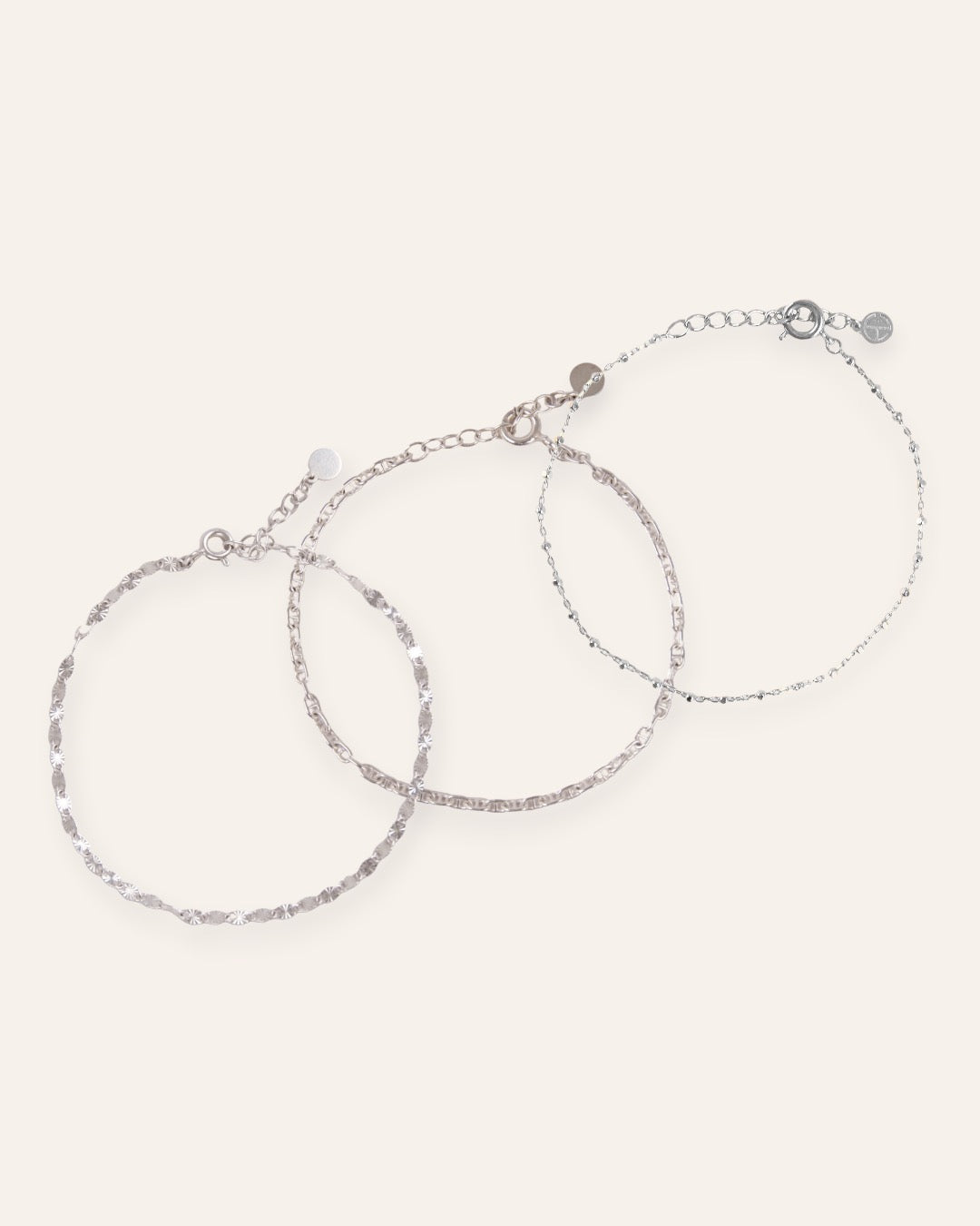 Composition de trois bracelets, avec un bracelet en chaîne avec des mailles soleil striées, un bracelet en chaîne marine, et un bracelet en chaîne fine avec des petites mailles carrées en argent massif 925.