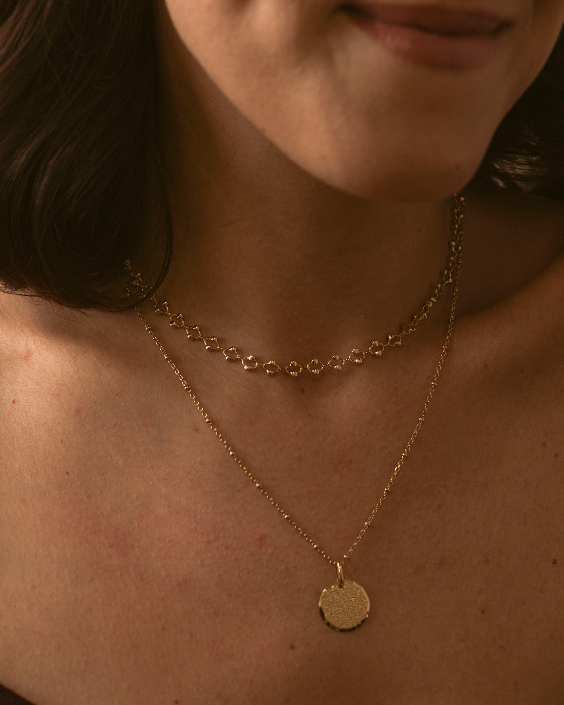 Combinaison de colliers durables en plaqué or 18 carats, avec un collier ras de cou avec une chaîne en maille ovale avec des petites perles dorées, et d'un collier en chaîne boule avec une médaille gravable, fabriqués en France.