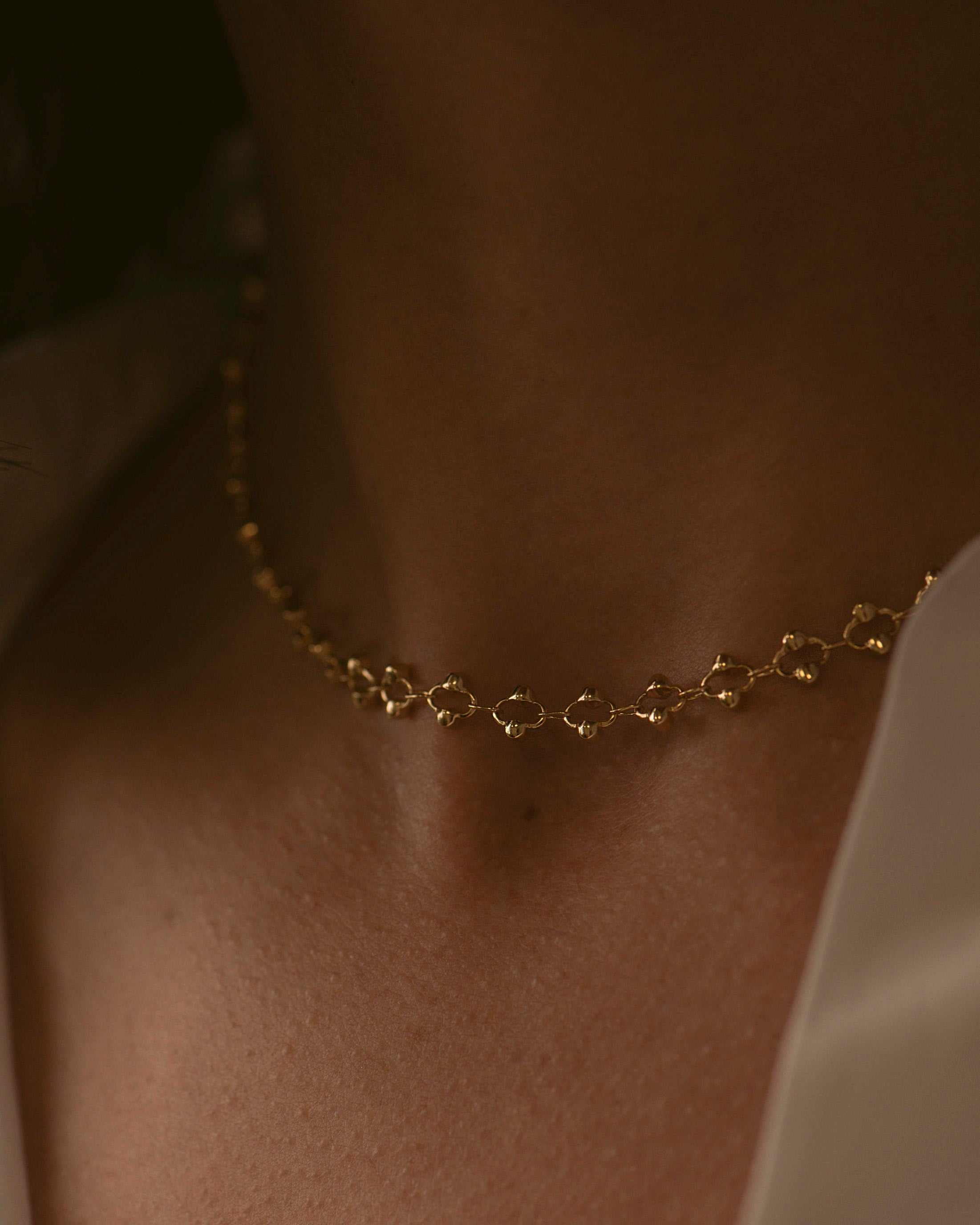 Collier ras de cou composé d'une chaîne avec des mailles ovales ornées de petites perles dorées sur les côtés, en plaqué or 3 microns 18 carats made in France.