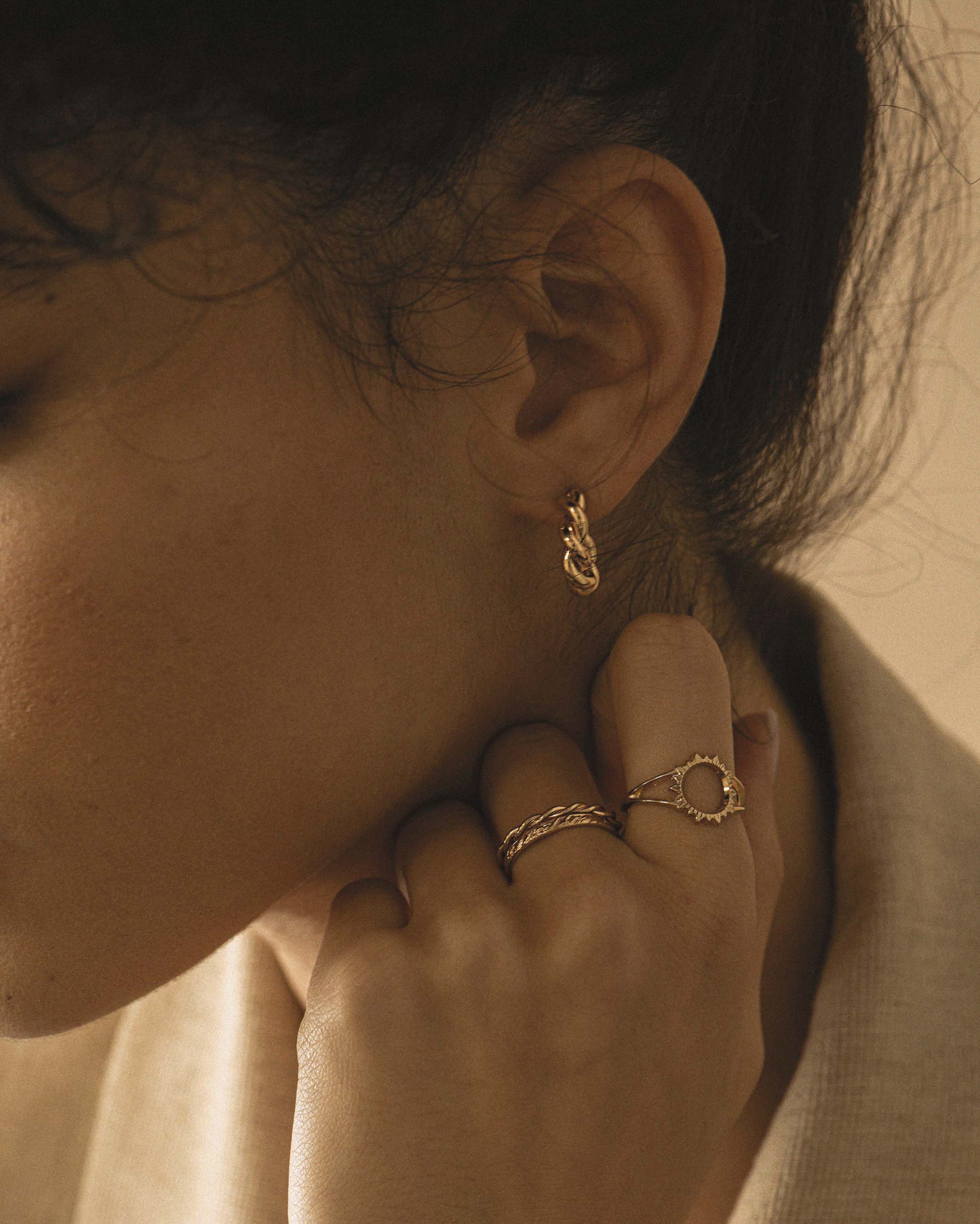 Association de bijoux tendances en plaqué or, composée de petites créoles torsadées, d'une bague ajustable torsadée, d'une bague ajustable au style vintage, et d'une bague au design soleil made in France.