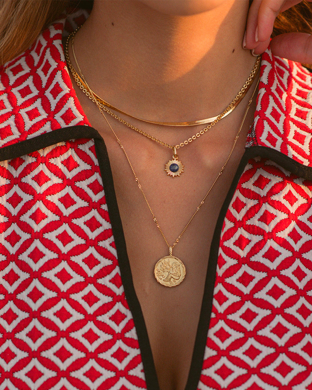 Association de colliers en plaqué or 3 microns composée d'un collier chaîne plate, d'un collier en maille soleil avec un pendentif en soleil avec une pierre éthique en lapis-lazuli, et d'un collier en maille fine avec un médaillon made in France.